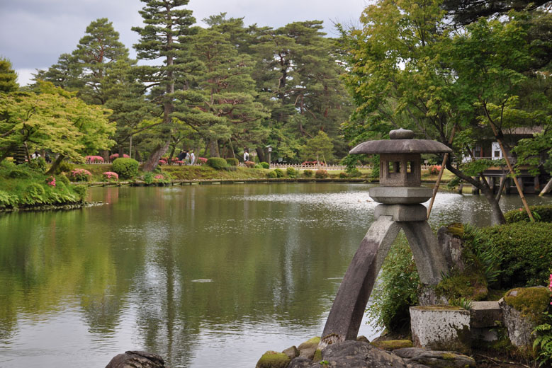 One of the the many stone lanterns at Kenroku-en garden, with a calm lake in the background, Kanazawa, Ishikawa Prefecture